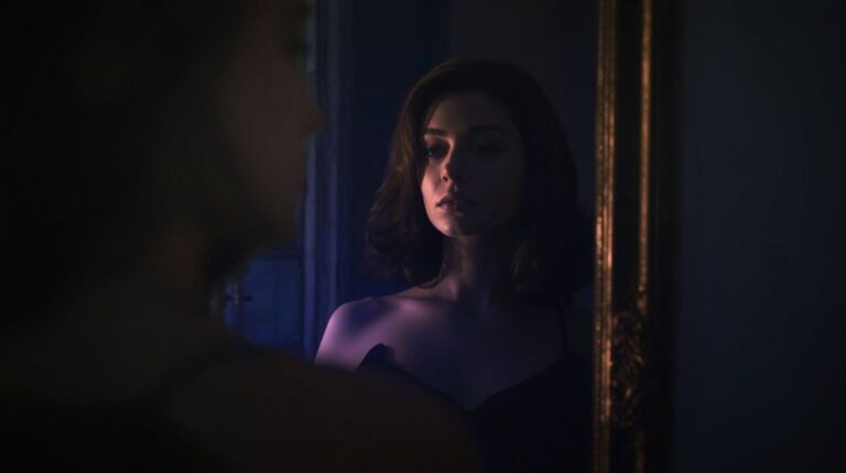 A woman gazes into her reflection as sunlight and shadow merge, symbolizing awakening and self-recognition.