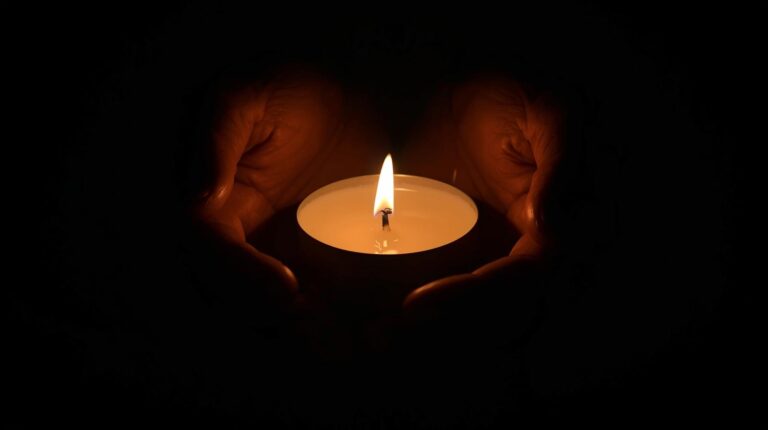 Hands holding a candle in soft twilight, symbolizing the first spark of awakening.